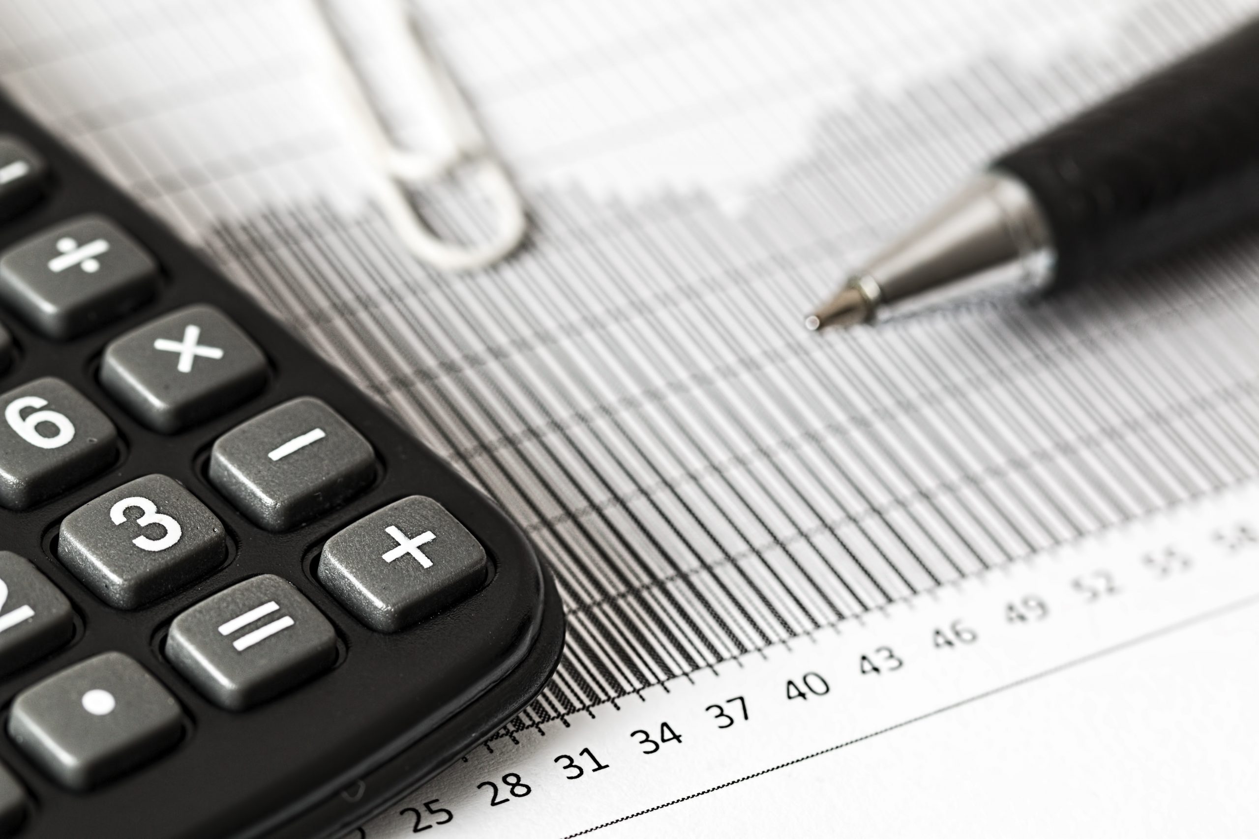 Foto de uma calculadora, uma folha com vários números e de uma caneta para a pauta "Retenção de impostos para condominios" do Blog da Estasa.